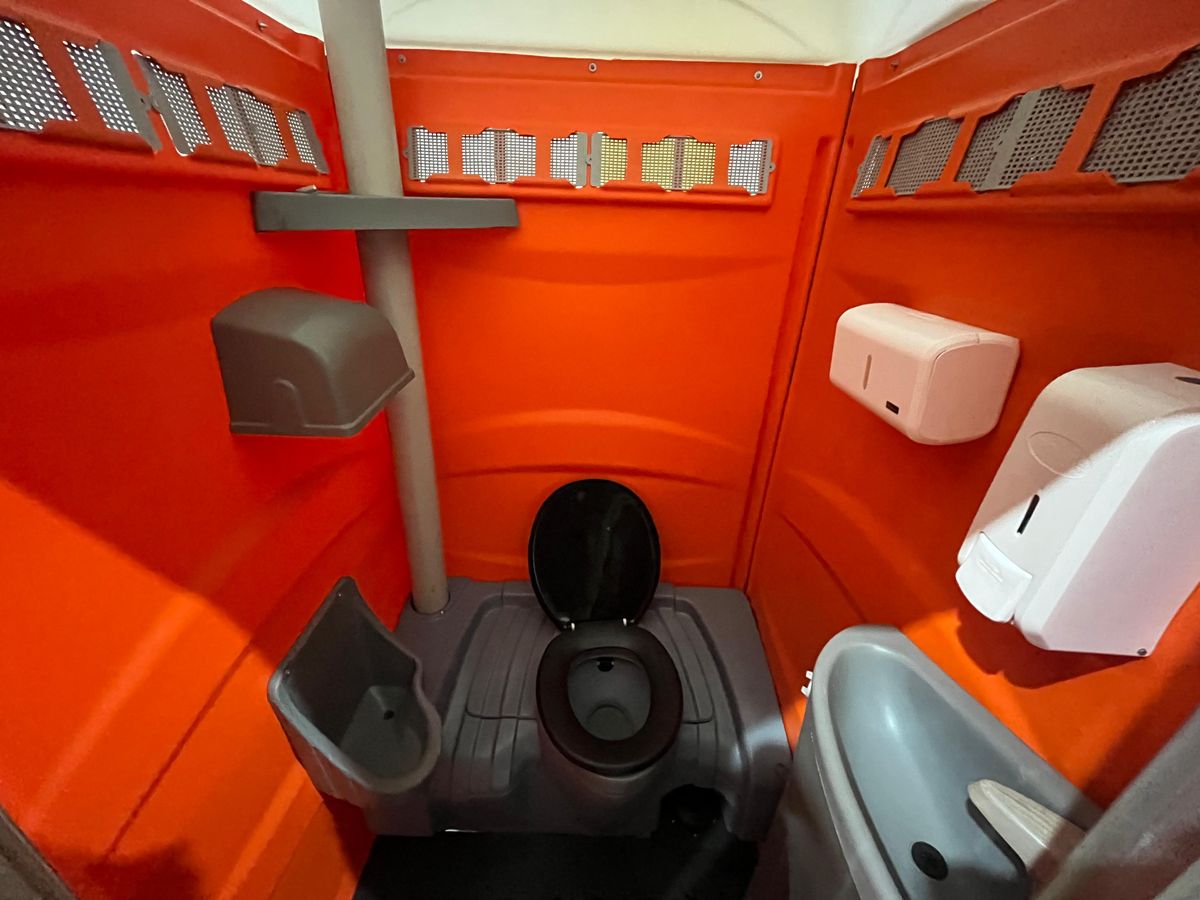 Interior limpo da cabine com vaso, mictório, pia e dispensers